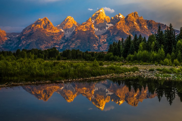 Colorful image of Grand Teton mountains and their reflection in a nearby lake.