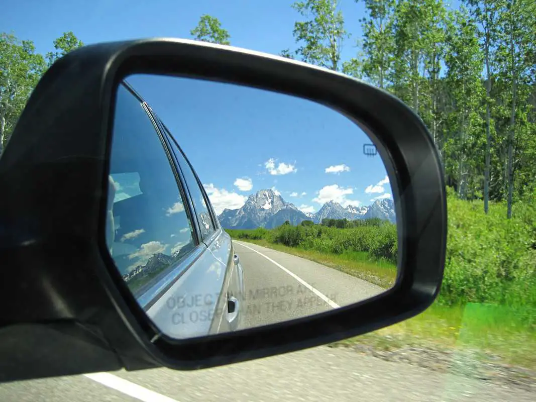 Side mirror in car showing reflection of the Grand Tetons