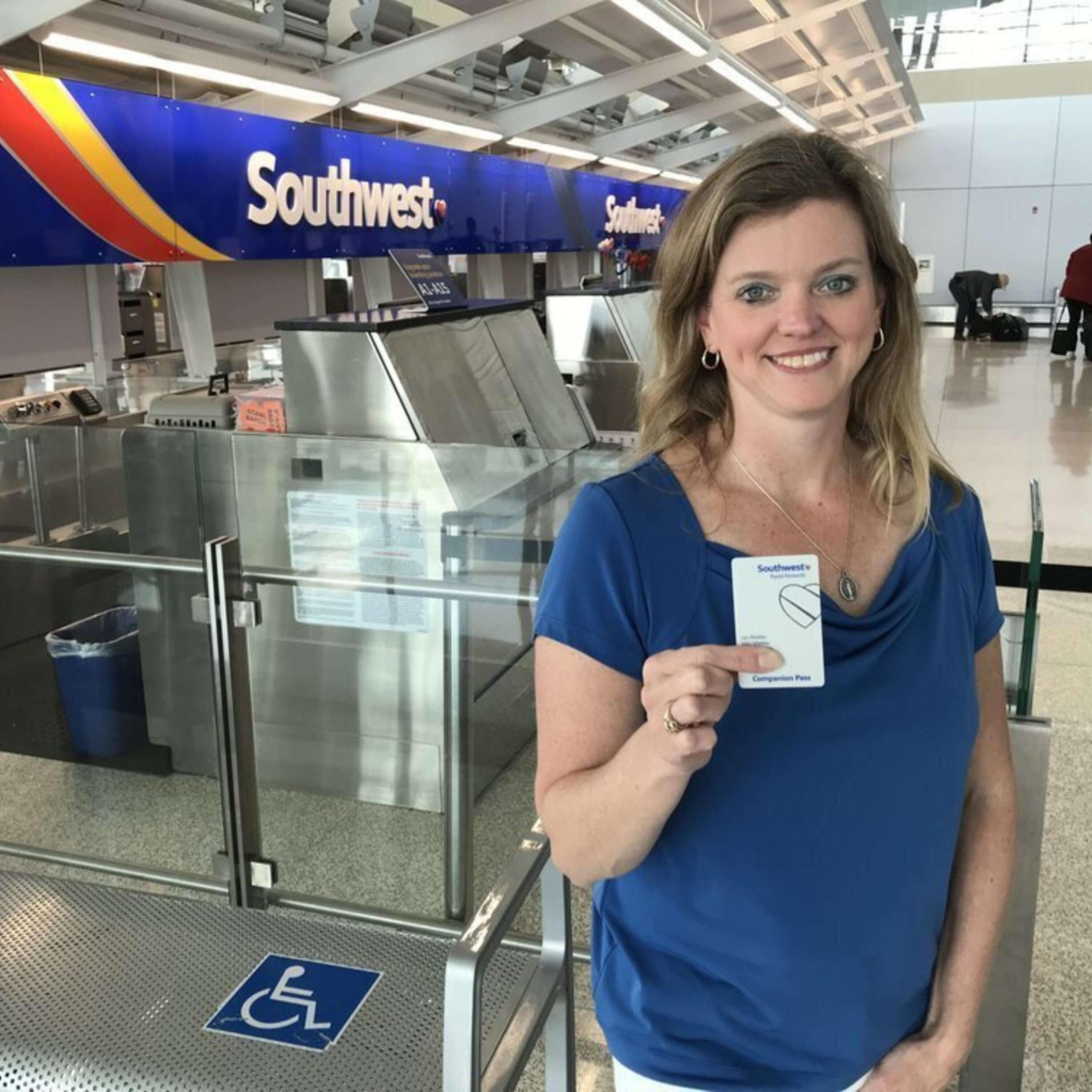 A woman is standing in front of an airport holding a ticket.