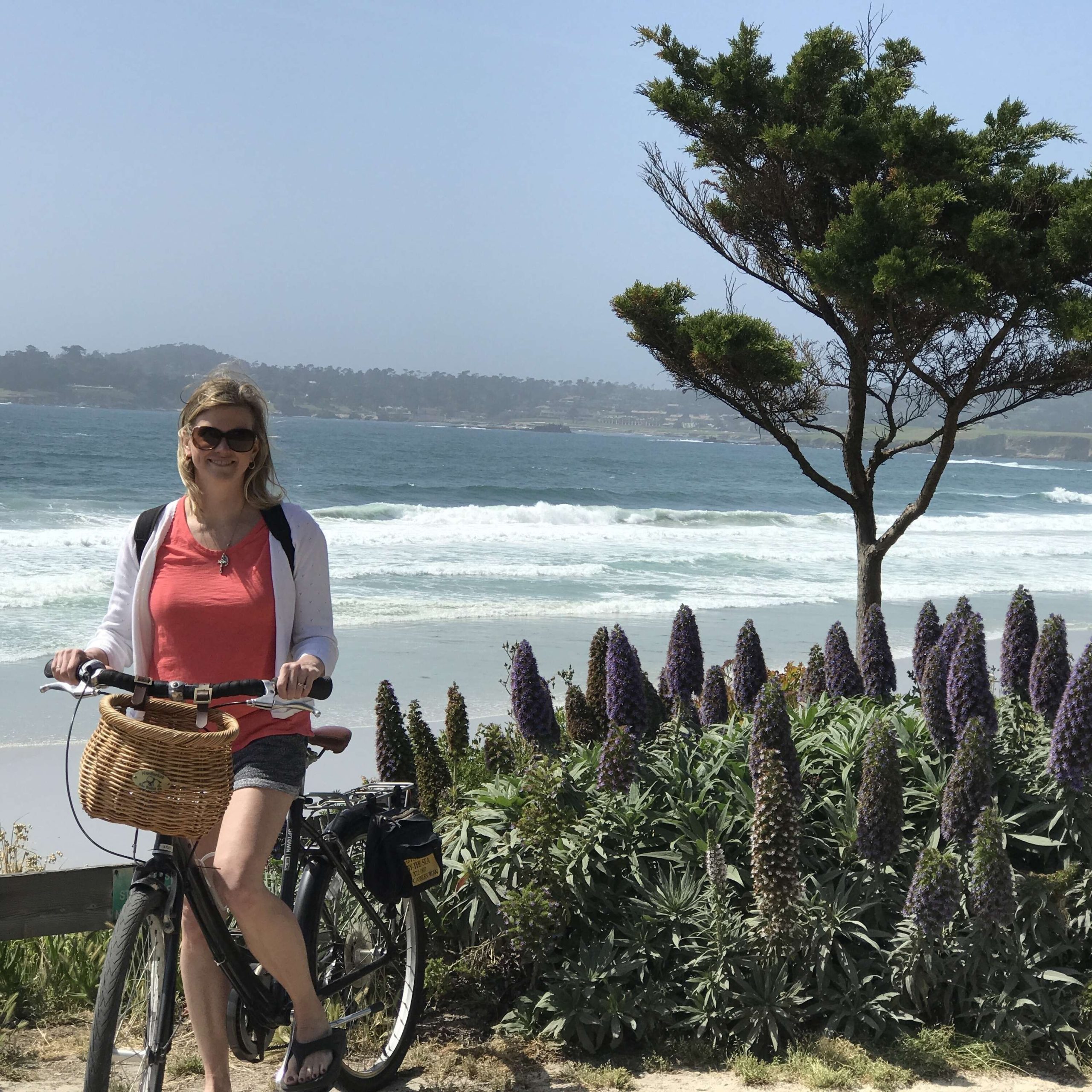 A woman on a bicycle next to the ocean.