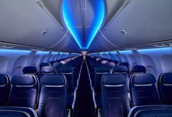 The inside of a new Southwest airplane with blue seats and blue lights.