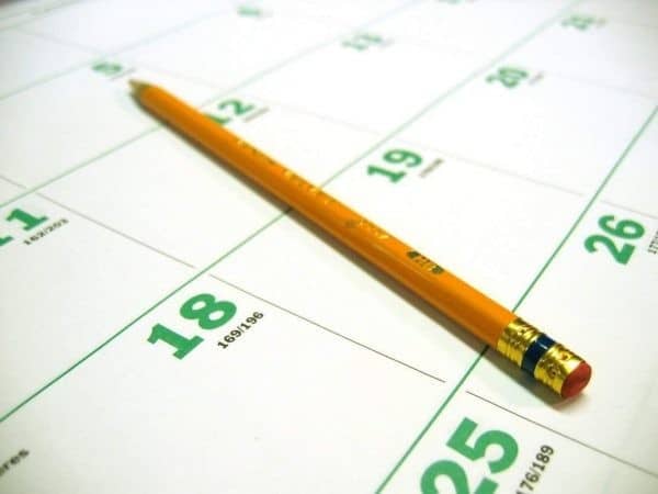 A pencil sits on top of a calendar.