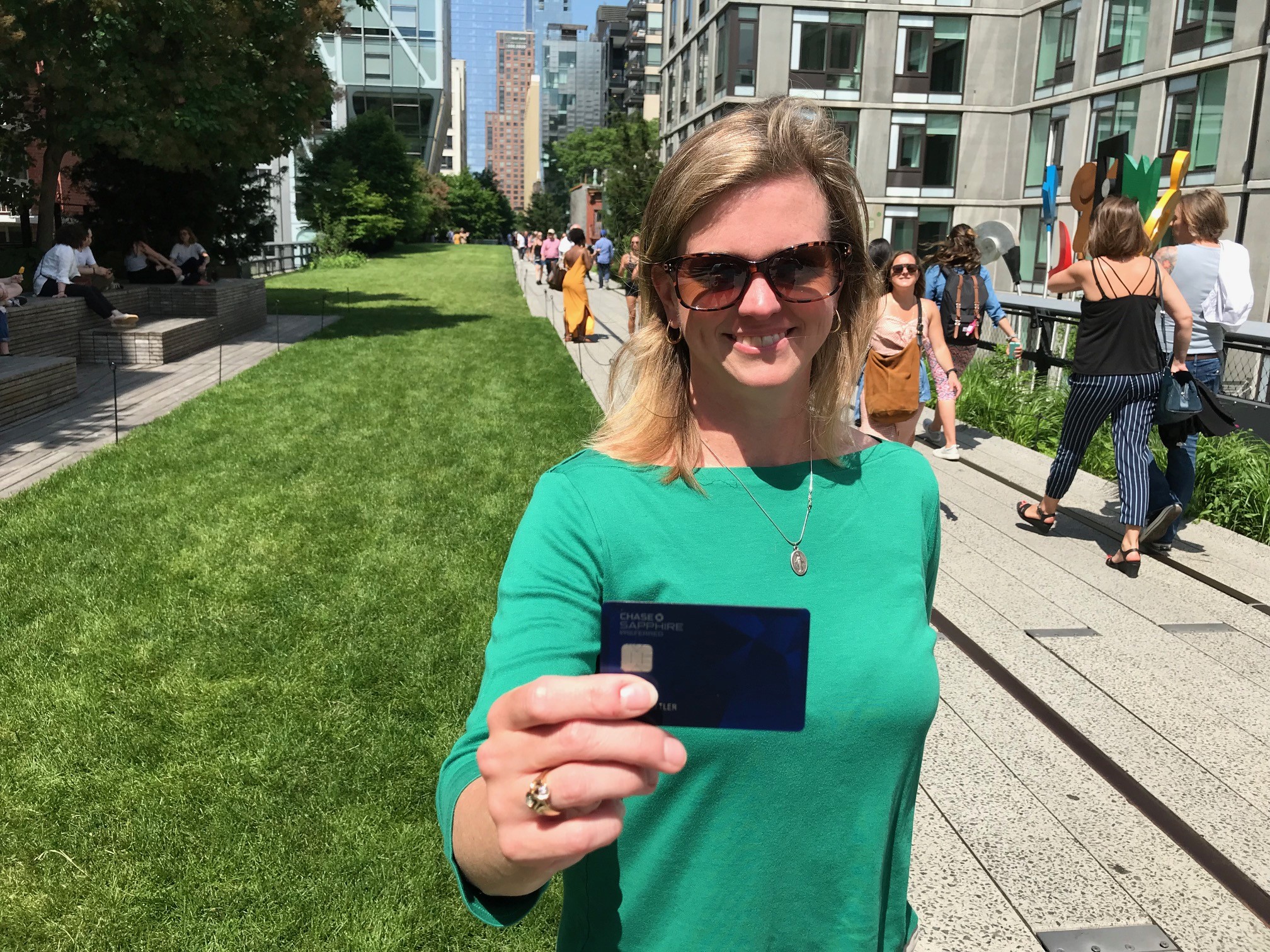 A woman proudly displaying the Southwest Priority Card on a sidewalk.