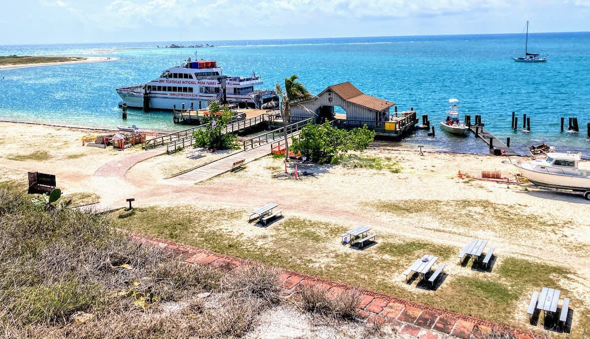 An aerial view of a beach in Dry Tortugas National Park with a boat docked in the water.