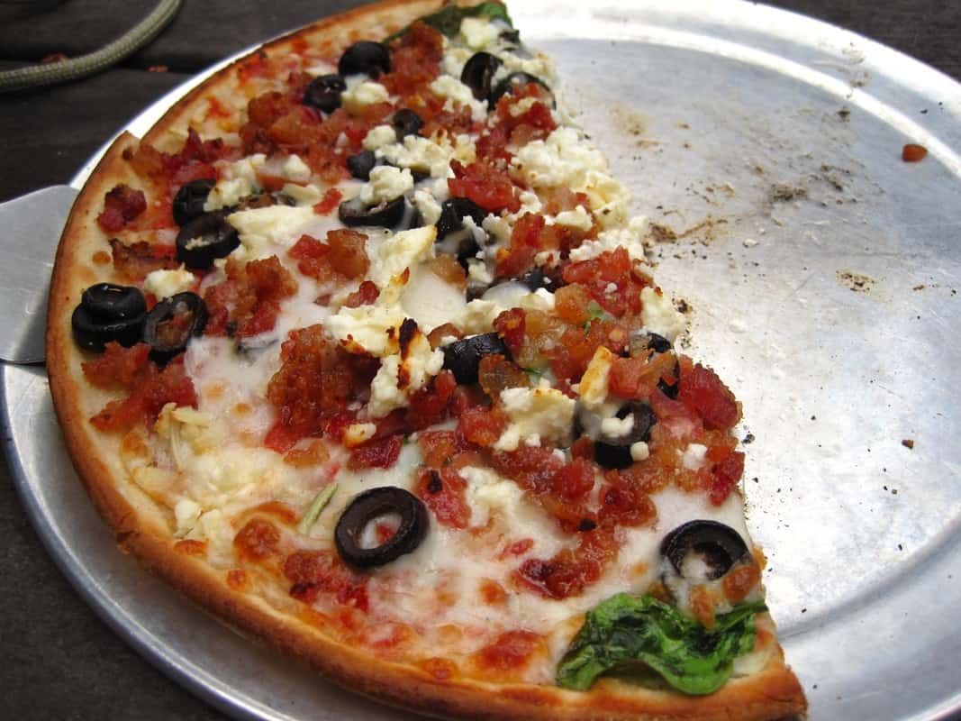 Half-eaten pizza on a round silver tray at Leek's Marina