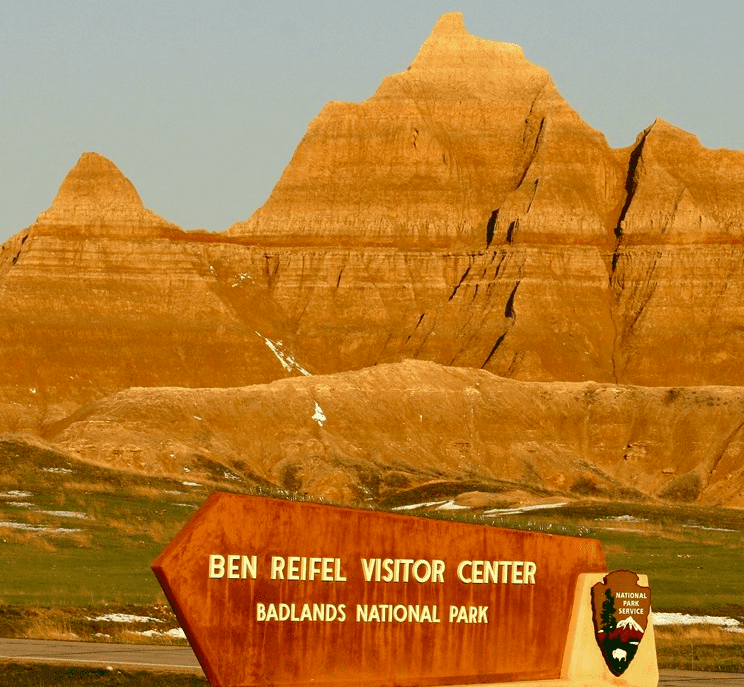 Sign for Badlands National Park Ben Reifel Visitor Center with mountain in background