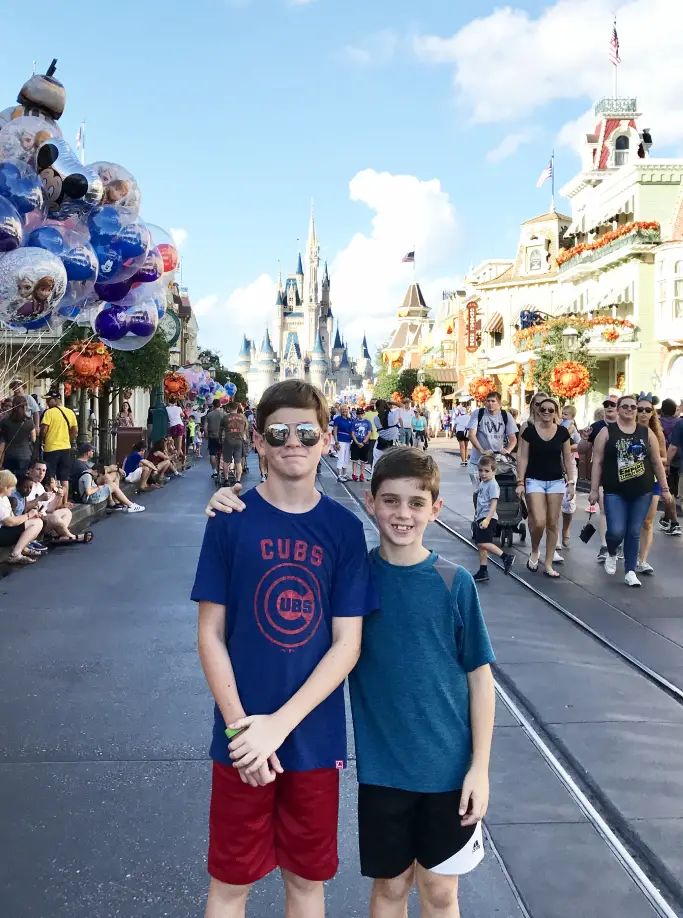 Two boys standing in front of cinderella's castle.