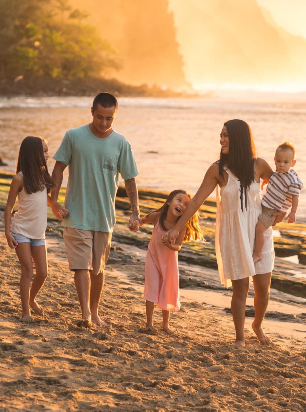 A family walking on the beach at sunset.