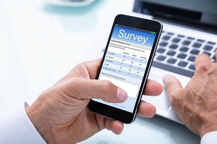 A hand holding a smartphone with a survey on it.