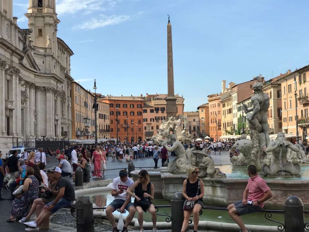 A group of people enjoying a casual activity in front of a famous Roman fountain.