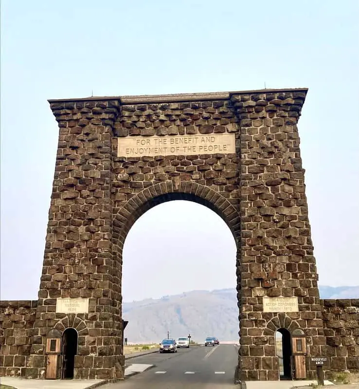 Roosevelt Arch in Yellowstone with cars and mountains in background