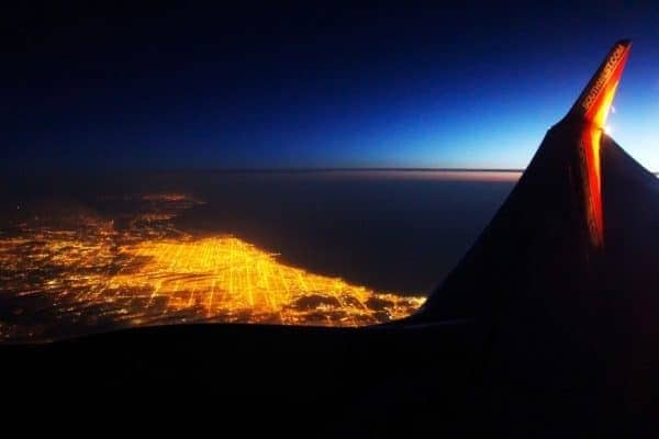 The wing of an airplane flying over a city at night.